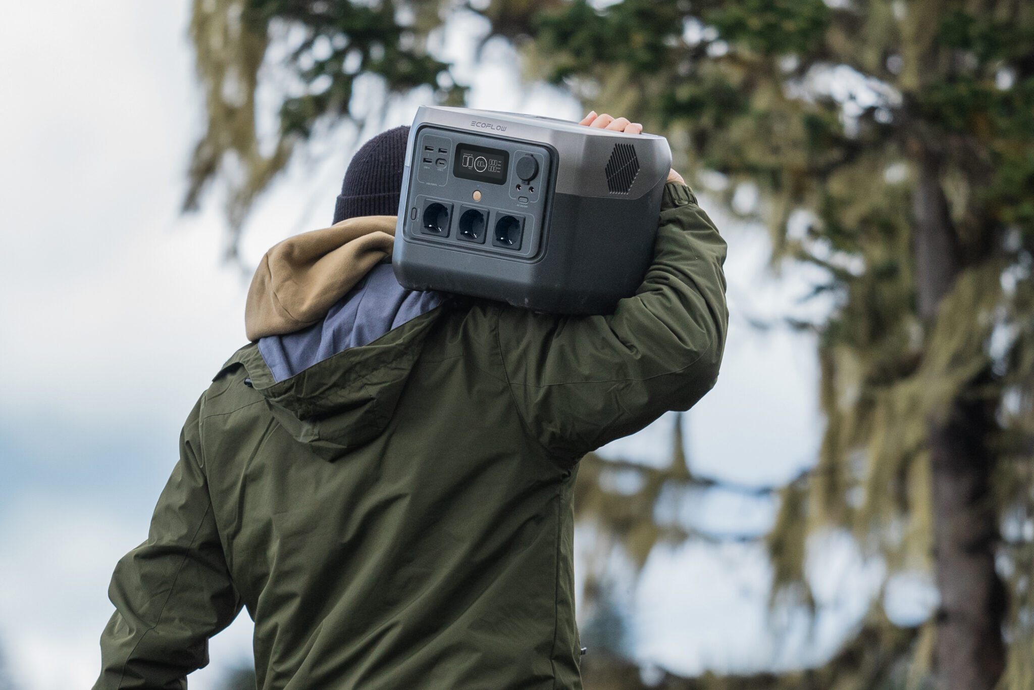 A man carrying an EcoFlow battery while camping outdoors.